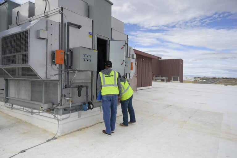 Two Chugach employees work on a mechanical system at a military base